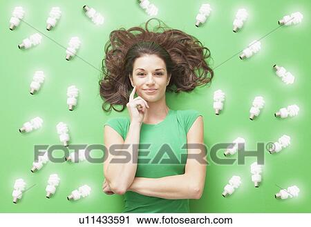 Girl laying on Green background with CF light bulbs around her View Large Photo Image Stock Image - Girl laying on Green background with CF light bulbs around her. Fotosearch