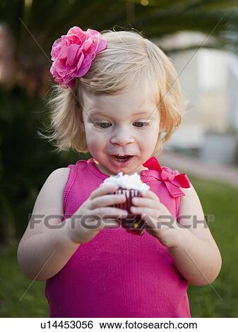 Girl with blong hair looking at cupcake View Large Photo Image Stock Photograph - Girl with blong hair looking at cupcake. Fotosearch