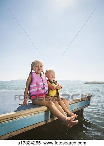 Stock Photography - Girls (2-3, 4-5) sitting at the edge of raft in life jackets. Fotosearch