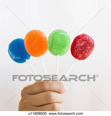 Hand holding colorful lollypops View Large Photo Image Stock Image - Hand holding colorful lollypops. Fotosearch