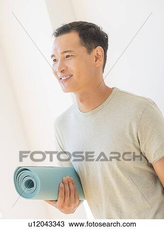 Happy mid adult man holding exercising mat View Large Photo Image Stock Image - Happy mid adult man holding exercising mat. Fotosearch