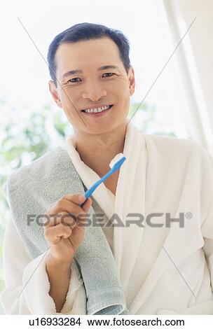 Picture - Happy mid adult man holding toothbrush. Fotosearch