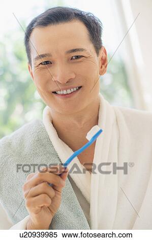 Stock Photography - Happy mid adult man holding toothbrush. Fotosearch
