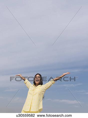 Stock Image - Happy woman against blue sky . Fotosearch