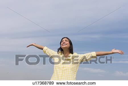 Stock Photo - Happy woman against blue sky . Fotosearch