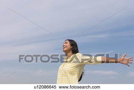 Stock Photography - Happy woman against blue sky . Fotosearch