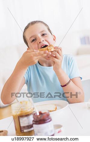 Happy young girl (8-9) having breakfast View Large Photo Image Stock Photo - Happy young girl (8-9) having breakfast. Fotosearch