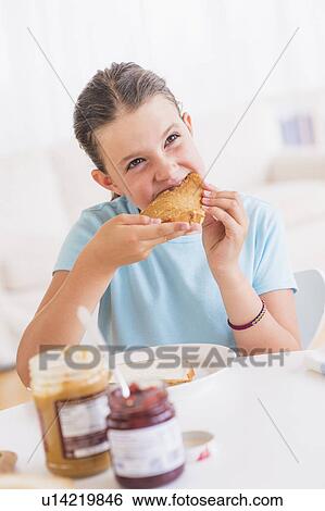 Happy young girl (8-9) having breakfast View Large Photo Image Stock Photograph - Happy young girl (8-9) having breakfast. Fotosearch
