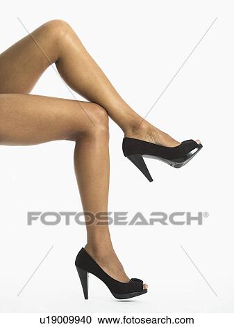 Stock Image - Low section of woman wearing high heels, studio shot. Fotosearch