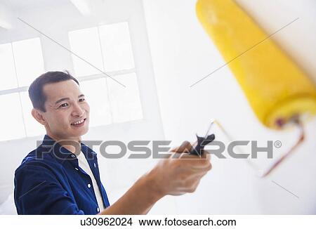 Picture - Man painting wall with painting roll. Fotosearch