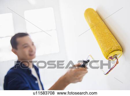 Stock Photo - Man painting wall with painting roll. Fotosearch