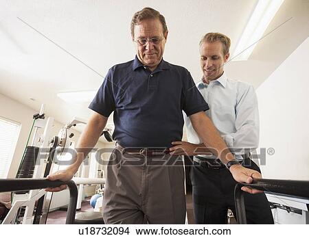 Man re-learning to walk with physical therapist View Large Photo Image Picture - Man re-learning to walk with physical therapist. Fotosearch
