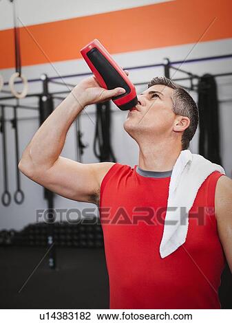 Mature man drinking while taking break from exercising View Large Photo Image Stock Image - Mature man drinking while taking break from exercising. Fotosearch