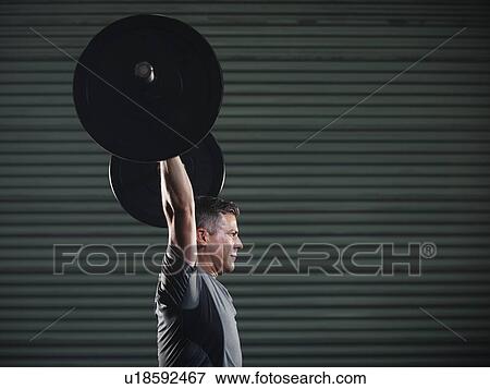 Mature man lifting heavy barbell View Large Photo Image Stock Photo - Mature man lifting heavy barbell . Fotosearch