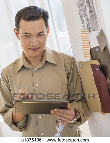 Stock Image - Mid adult fashion designer using digital tablet. Fotosearch