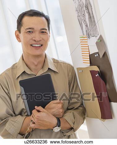 Stock Photograph - Mid adult fashion designer using digital tablet. Fotosearch
