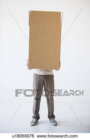 Stock Photograph - Mid adult man hiding inside of cardboard box. Fotosearch