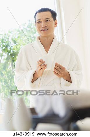 Stock Photo - Mid adult man holding cup of healthy herbal tea. Fotosearch