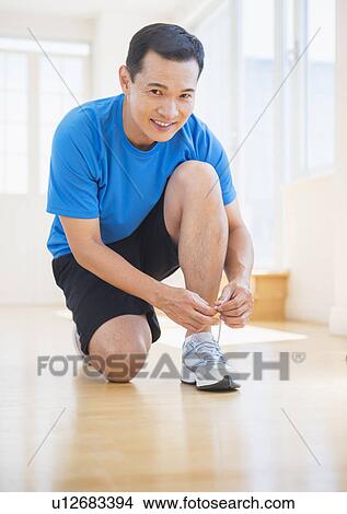 Picture - Mid adult man lacing his running shoes. Fotosearch