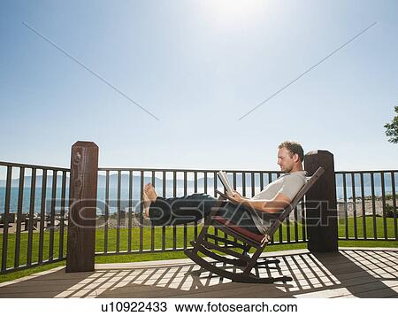 Mid-adult man relaxing on rocking chair View Large Photo Image Stock Image - Mid-adult man relaxing on rocking chair. Fotosearch