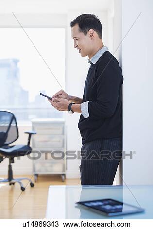 Stock Image - Mid adult man text messaging. Fotosearch