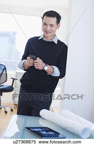 Stock Photography - Mid adult man text messaging. Fotosearch