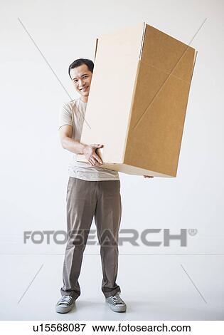 Stock Photo - Mid adult moving cardboard boxes. Fotosearch