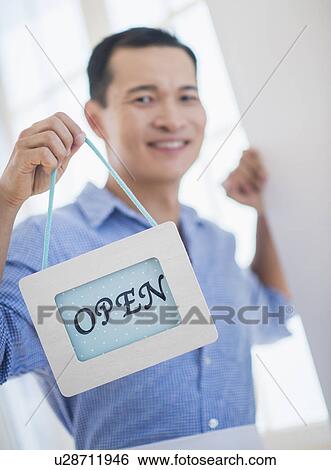 Mid adult waiter holding open sign View Large Photo Image Stock Photograph - Mid adult waiter holding open sign. Fotosearch