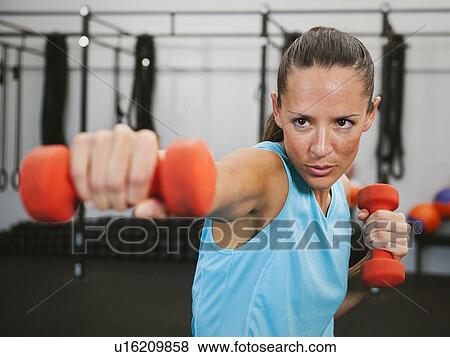 Stock Photo - Mid adult woman exercising with dumbbells. Fotosearch
