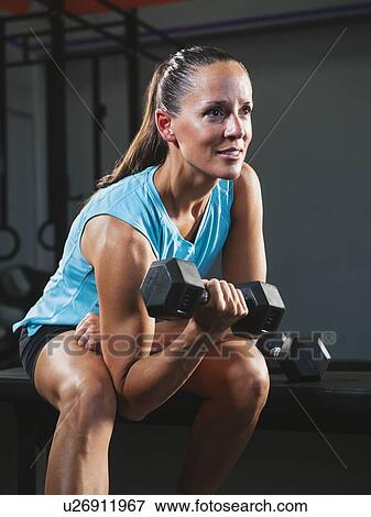 Mid adult woman exercising with dumbbells View Large Photo Image Stock Photo - Mid adult woman exercising with dumbbells. Fotosearch