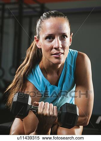 Mid adult woman exercising with dumbbells View Large Photo Image Stock Photography - Mid adult woman exercising with dumbbells. Fotosearch