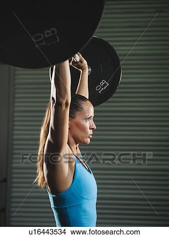 Picture - Mid adult woman lifting barbell . Fotosearch