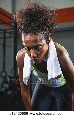 Stock Photograph - Mid adult woman taking break from exercising. Fotosearch