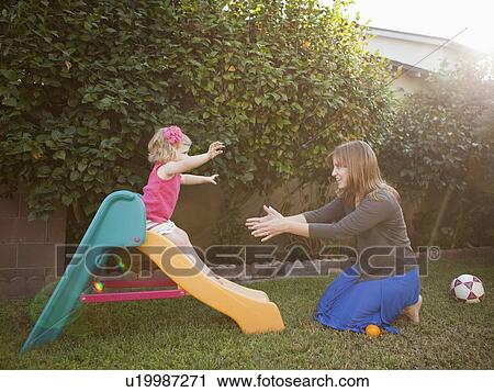 Stock Image - Mother and her daughter playing in backyard. Fotosearch