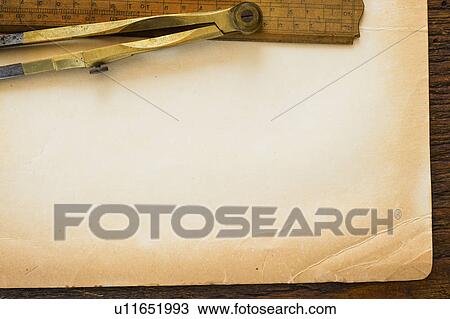 Stock Image - Old brown paper with ruler and compass, studio shot. Fotosearch