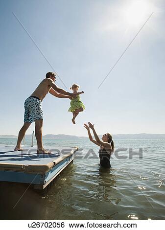 Parents playing with their daughter (2-3) in lake View Large Photo Image Stock Photograph - Parents playing with their daughter (2-3) in lake. Fotosearch