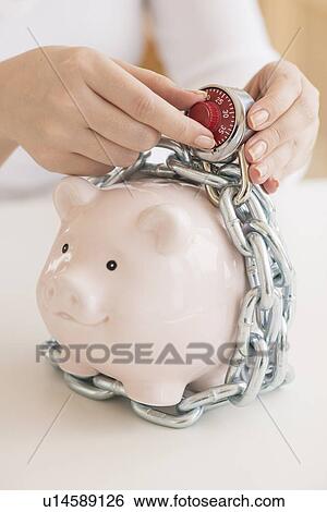 Stock Photograph - Piggybank closed with chain and combination lock. Fotosearch