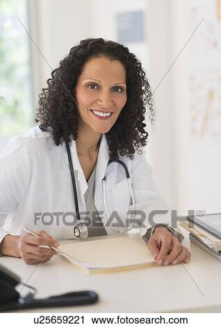 Portrait of doctor sitting in office View Large Photo Image Stock Image - Portrait of doctor sitting in office. Fotosearch