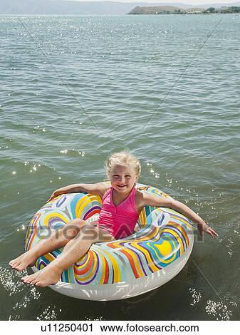 Stock Image - Portrait of girl (4-5) floating on water on inflatable ring. Fotosearch