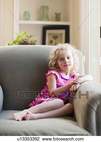 Stock Image - Portrait of girl (4-5) sitting on armchair. Fotosearch