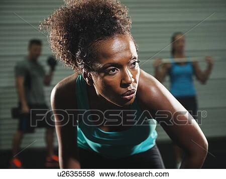 Stock Photo - Portrait of mid adult woman in gym with people exercising in background. Fotosearch