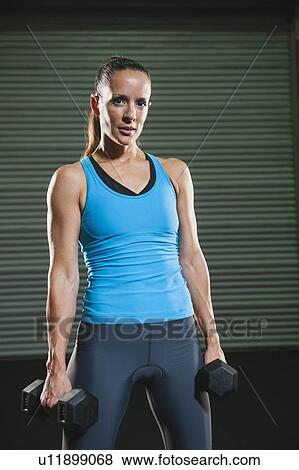 Stock Photo - Portrait of mid adult woman with free weights. Fotosearch