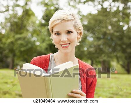 Portrait of smiling woman holding book View Large Photo Image Picture - Portrait of smiling woman holding book. Fotosearch