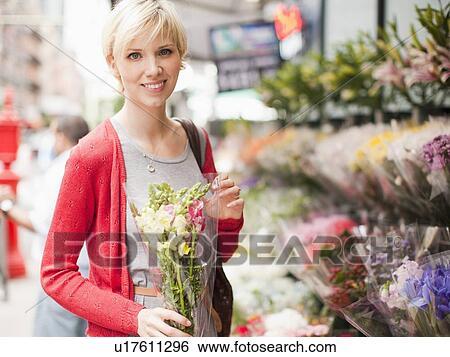 Portrait of smiling woman holding bunch of flowers outside of florist shop View Large Photo Image Stock Photograph - Portrait of smiling woman holding bunch of flowers outside of florist shop. Fotosearch