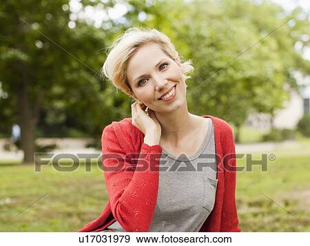 Portrait of smiling woman in park View Large Photo Image Stock Photo - Portrait of smiling woman in park. Fotosearch