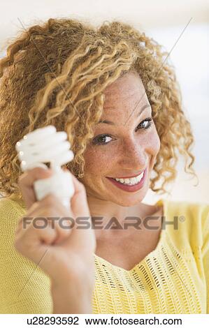 Portrait of smiling young woman holding light bulb View Large Photo Image Stock Image - Portrait of smiling young woman holding light bulb. Fotosearch
