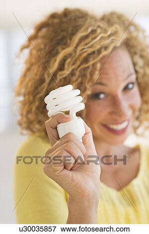 Portrait of smiling young woman holding light bulb View Large Photo Image Stock Photo - Portrait of smiling young woman holding light bulb. Fotosearch