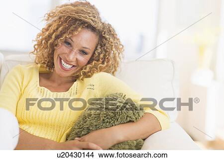 Portrait of smiling young woman sitting on sofa View Large Photo Image Picture - Portrait of smiling young woman sitting on sofa. Fotosearch