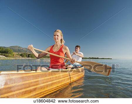 Stock Image - Portrait of two young people paddling canoe. Fotosearch