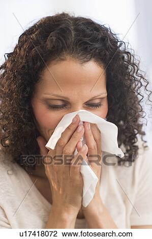 Stock Image - Portrait of woman blowing nose. Fotosearch